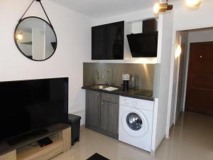 ein Wohnzimmer mit einer Waschmaschine und einem TV in der Unterkunft Studio résidence Golfe Marine avec piscine et parking in Vallauris