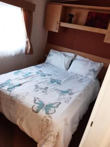 a bed with a white bedspread with butterflies on it at BUTLINS SKEGNESS, 3 Beds, Pet Friendly - The Paddock in Lincolnshire