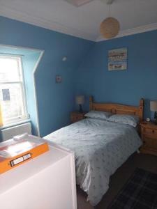 1 dormitorio con 1 cama con pared azul en Bank House, en Thurso