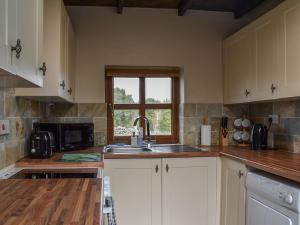 a kitchen with white cabinets and a sink and a window at Tyr Eithin Bach in Pont Yates