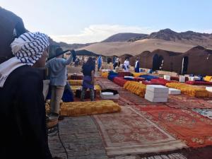 een groep mensen die tapijten bekijken in de woestijn bij Hostel Amour d'auberge in Marrakesh