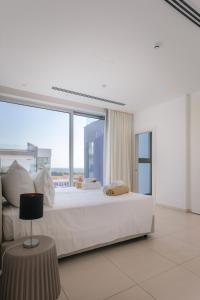 a white bedroom with a large bed with a large window at Cove Seaview Villas - Neptune in Ayia Napa +141 photos