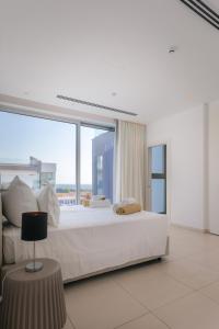 a white bedroom with a large bed with a large window at Cove Seaview Villas - Neptune in Ayia Napa