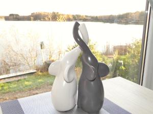 zwei Skulpturen von Kaninchen, die auf einem Tisch sitzen und aus dem Fenster schauen in der Unterkunft Chalet am See in Wackersdorf