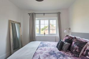 a bedroom with a large bed with a mirror at Fairway - modern and stylish holiday home in Kent