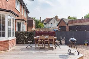a patio with a table and chairs and a fence at Fairway - modern and stylish holiday home in Kent