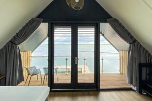 a bedroom with a large glass door leading to a deck at Waterrijk Oesterdam Resort Villas in Tholen