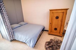 a small bedroom with a bed and a wooden cabinet at Les Tilleuls 22 - balcon vue montagne in Orcières