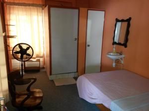 um quarto com uma cama, um lavatório e uma cadeira em Guesthouse AlbergoAlberga em Paramaribo