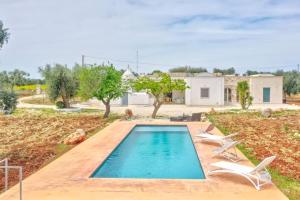 una piscina con 2 sillas y una casa en Bianco Trullo by Raro Villas, en Latiano