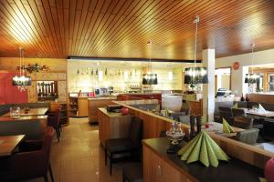 a restaurant with wooden ceilings and tables and chairs at Hotel Hellers Twenty Four II -24h-Check-In- in Friedrichshafen