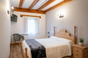a bedroom with a bed and a chair and a window at Casa Rural La Magdalena in Hoz de Anero