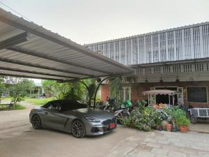 a silver car parked under a canopy in front of a building at Aenguy Hostel in Sukhothai