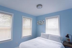 a blue bedroom with a bed and two windows at Central & Comfortable Home Walk to the Beach! in Jacksonville Beach