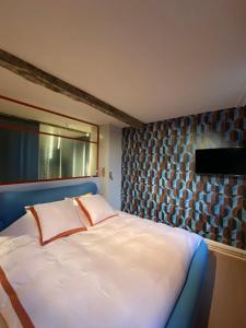 a bedroom with a large white bed with a window at Bed & Binnekyk in Mechelen