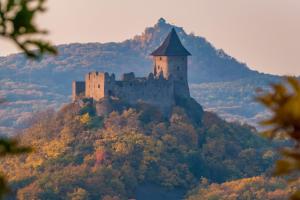a castle on top of a hill with trees at Karancs Apartman Salgótarján in Salgótarján