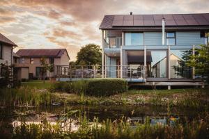 a house with a pond in front of it at Golden Lakes Village Ardennes in Boussu-lez-Walcourt