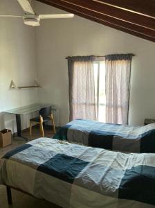 a bedroom with two beds and a desk and a window at Casa con vista a las sierras de Cordoba in Malagueño