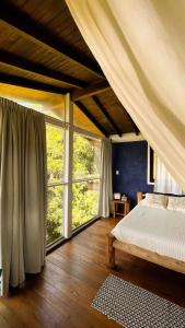 a bedroom with a bed and a large window at Casa Fluila in Praia do Rosa