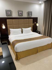1 dormitorio con 1 cama grande con almohadas blancas en جلنار الشرق للشقق المخدومة, en Yeda