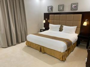1 dormitorio con 1 cama grande con sábanas y almohadas blancas en جلنار الشرق للشقق المخدومة, en Yeda