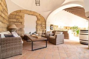 Una sala de estar con muebles de mimbre y una pared de piedra. en Loft Bodega San Blas con porche y parking, en Jerez de la Frontera