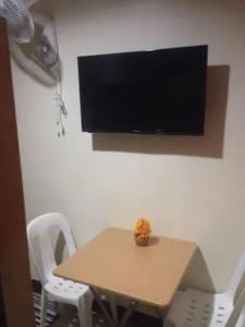 愛妮島的住宿－Lolo Bob's Bed And Breakfast，一张桌子、白色椅子和墙上的电视