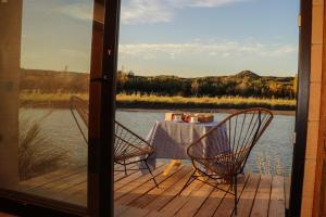 einen Tisch und Stühle auf einer Terrasse mit Seeblick in der Unterkunft Bodega Trina Suites in Río Colorado