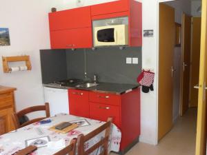 瓦盧瓦爾的住宿－Appartement Valloire, 2 pièces, 4 personnes - FR-1-263-129，厨房配有红色橱柜、桌子和微波炉