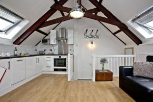 a kitchen with white cabinets and a black couch at Anchor Cottage, Strete, Dartmouth in Strete