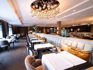 a restaurant with white tables and chairs and a bar at Van der Valk Hotel Vianen - Utrecht in Vianen