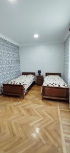 two beds in a room with wooden floors at EleGaya Guest house in Ijevan