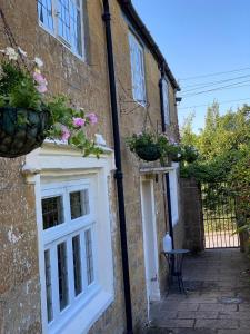 a building with a white door and potted plants on it at The Crown & Victoria Inn in Tintinhull