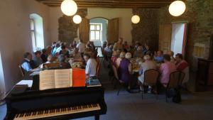 a group of people sitting at tables with a piano at Piotrowice Nyskie Palace in Otmuchów