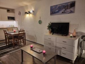 sala de estar con TV y mesa con velas en LE PLEIN SUD, en Les Deux Alpes