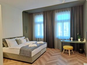 a bedroom with a bed and a desk and windows at Hotel Domus Collis in Győr