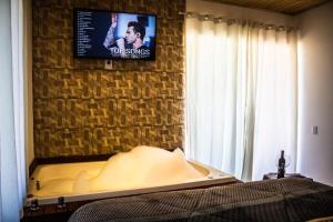 a bedroom with a bed and a tv on a wall at Império Cabanas in Urubici