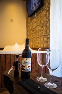 a bottle of wine and two glasses on a table at Império Cabanas in Urubici