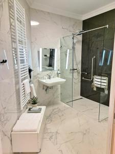 a white bathroom with a sink and a shower at Hotel Domus Collis in Győr