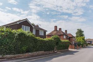 a house with a hedge in front of a street at St George's - stylish family home in Sandwich in Kent