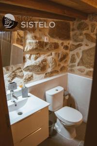 a bathroom with a toilet and a stone wall at Casa da Carreirinha in Arcos de Valdevez