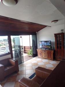 - un salon avec un canapé et une télévision dans l'établissement Casa em Geribá ampla duas suítes com piscina e vista dentro de condominio, à Búzios