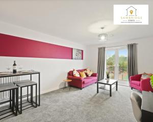 uma sala de estar com mobiliário rosa e uma parede vermelha em Beautiful 2 Bedroom Seviced Apt in Aylesbury By Sambridge Stays Short Lets & Serviced Accommodation em Aylesbury