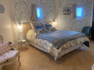 Schlafzimmer mit einem Bett, einem Stuhl und Fenstern in der Unterkunft Le nid 