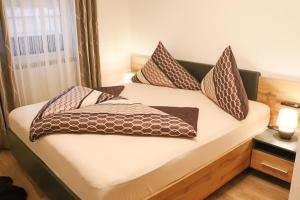 Una cama con almohadas marrones y blancas. en Ferienwohnung am Waldweg, en Kolsass