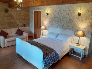 ein Schlafzimmer mit einem großen weißen Bett und einem Sofa in der Unterkunft The Byre North End Farm in Ashton Keynes