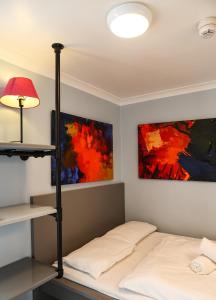a bedroom with a bed with a lamp and paintings at Astor Hyde Park Hostel in London