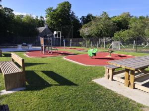 a park with two benches and a playground at La Mansarde in Magny-en-Bessin