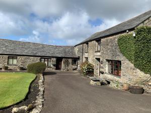 an old stone house with a driveway at Courtyard Farm Cottages in Boscastle