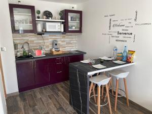 a kitchen with purple cabinets and a counter with stools at Superbe maison Tout Confort Parking Netflix in Ascoux +9 photos